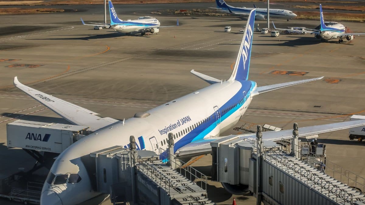 Aircraft parked at airport terminal with jet bridge, reflecting busy international travel.