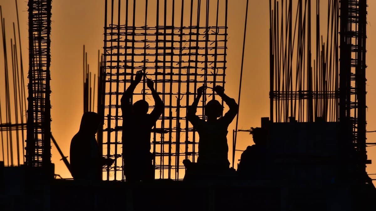 Silhouetted construction workers at a site during sunset, creating a dramatic scene.