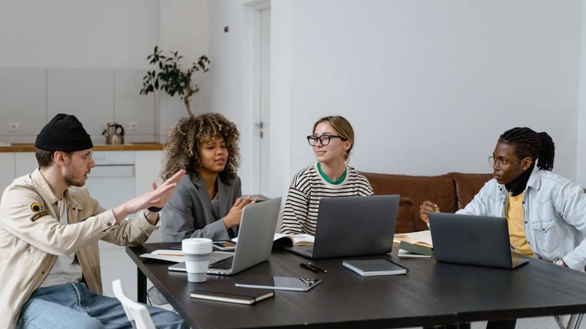 Group of diverse colleagues collaborating with laptops in a modern office setting.