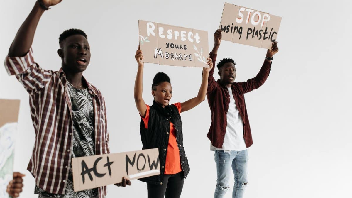 Young adults holding protest signs advocating for respect and environmental awareness.