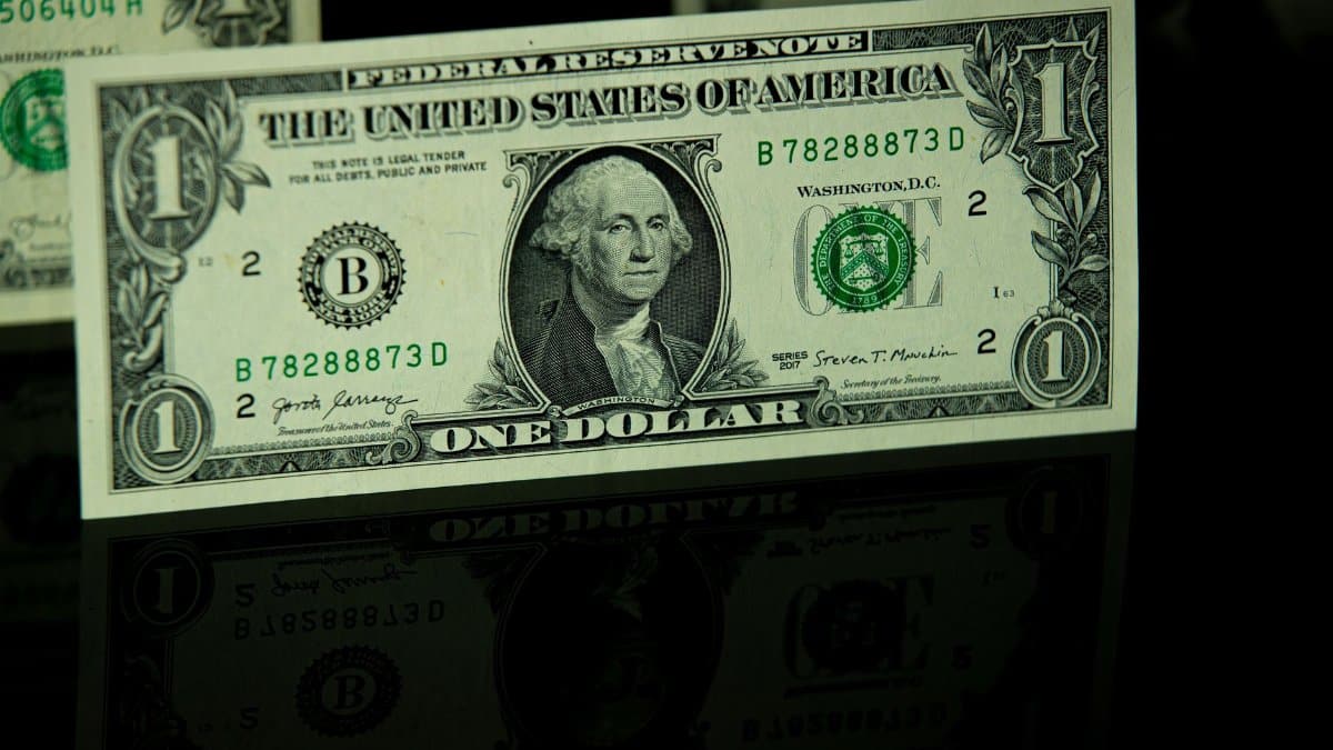 Detailed close-up of a US one-dollar bill with reflection, highlighting currency design.