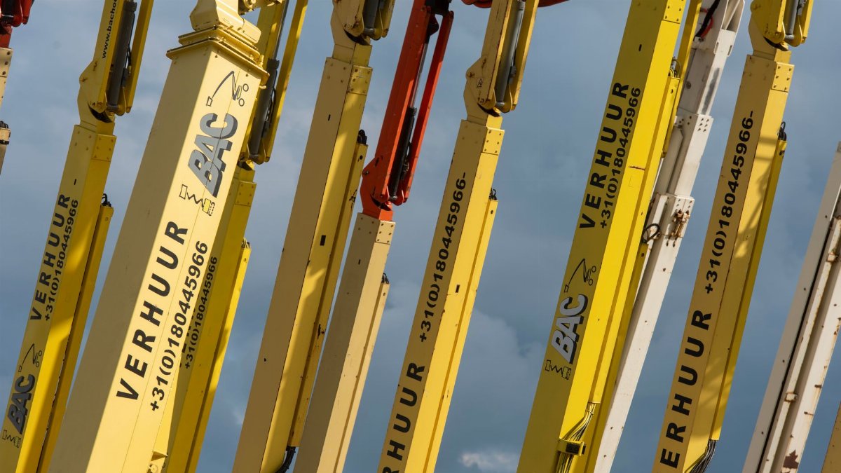 Multiple yellow boom lifts with text and numbers arranged against a blue sky.