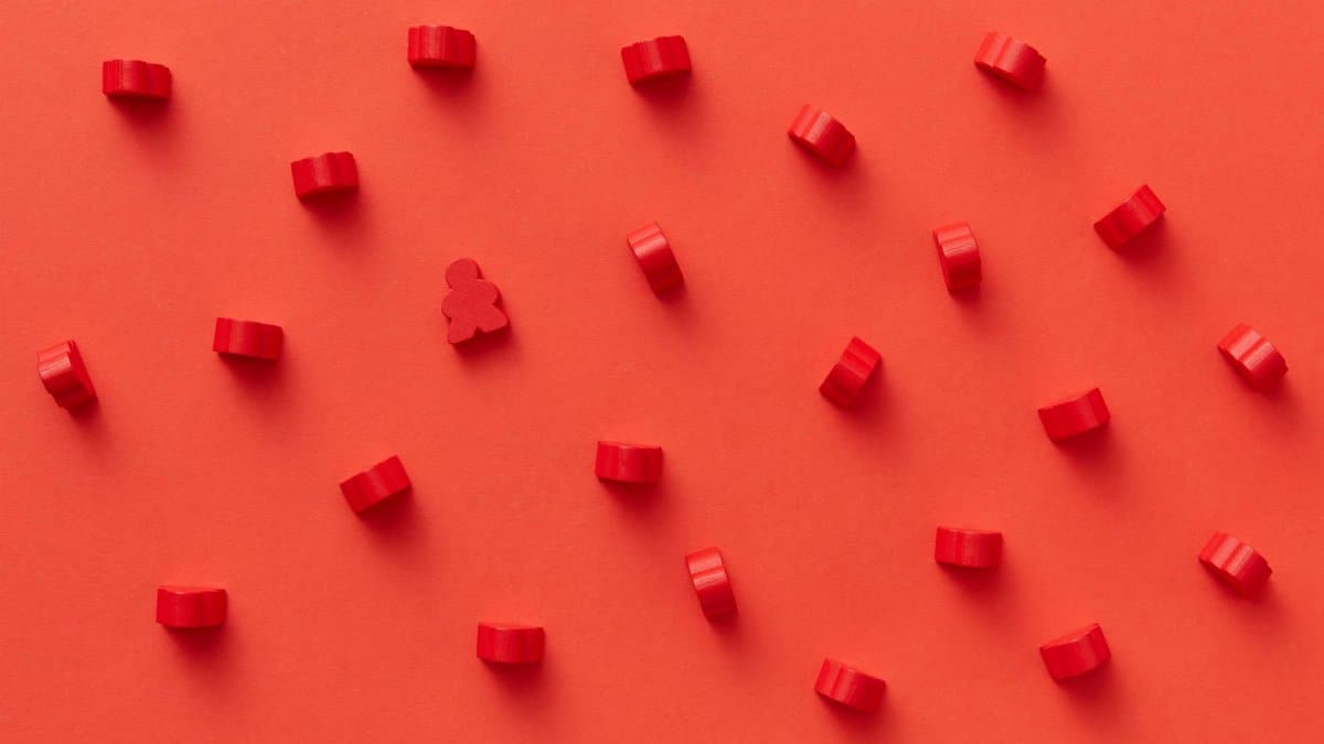 Flat lay of red board game pieces on a red background arranged in a pattern.
