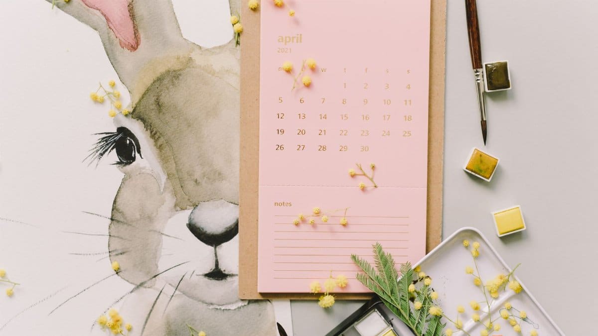 A watercolor Easter bunny illustration beside an April calendar and mimosa flowers, perfect for spring celebrations.