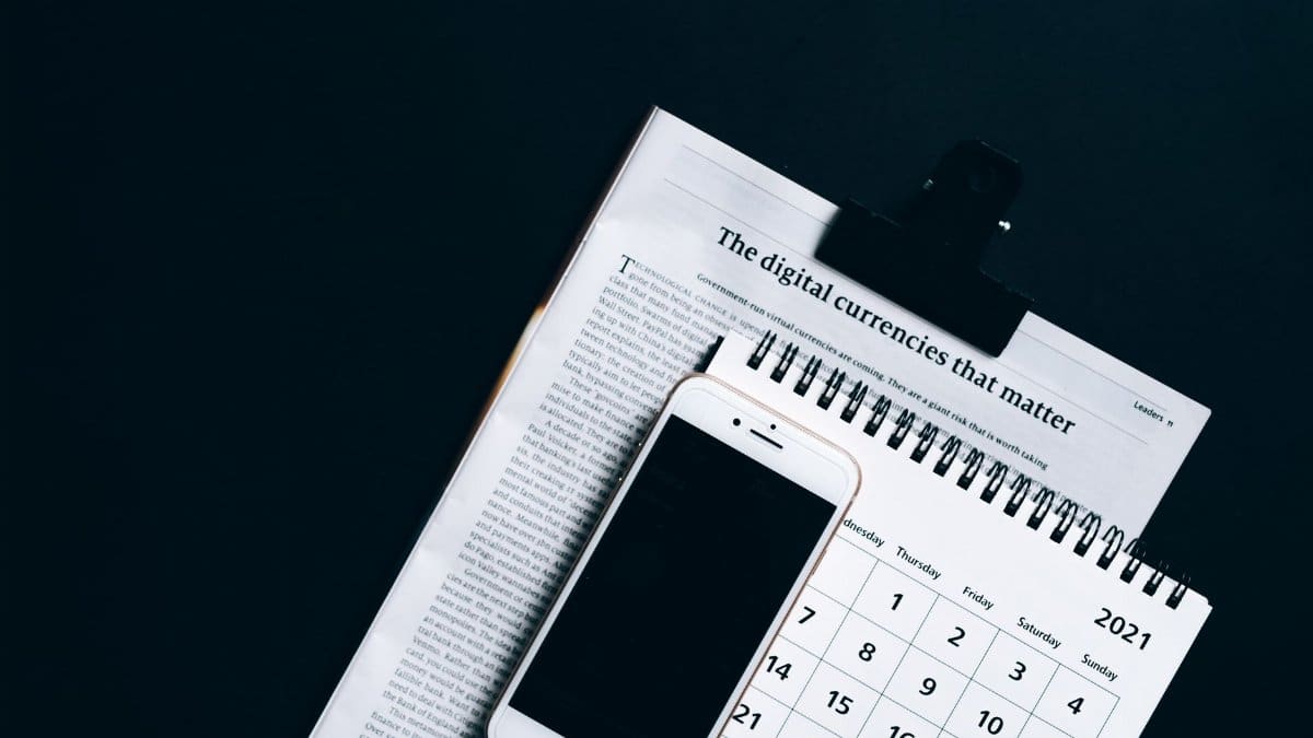 A smartphone placed on a newspaper and calendar, symbolizing modern digital finance.