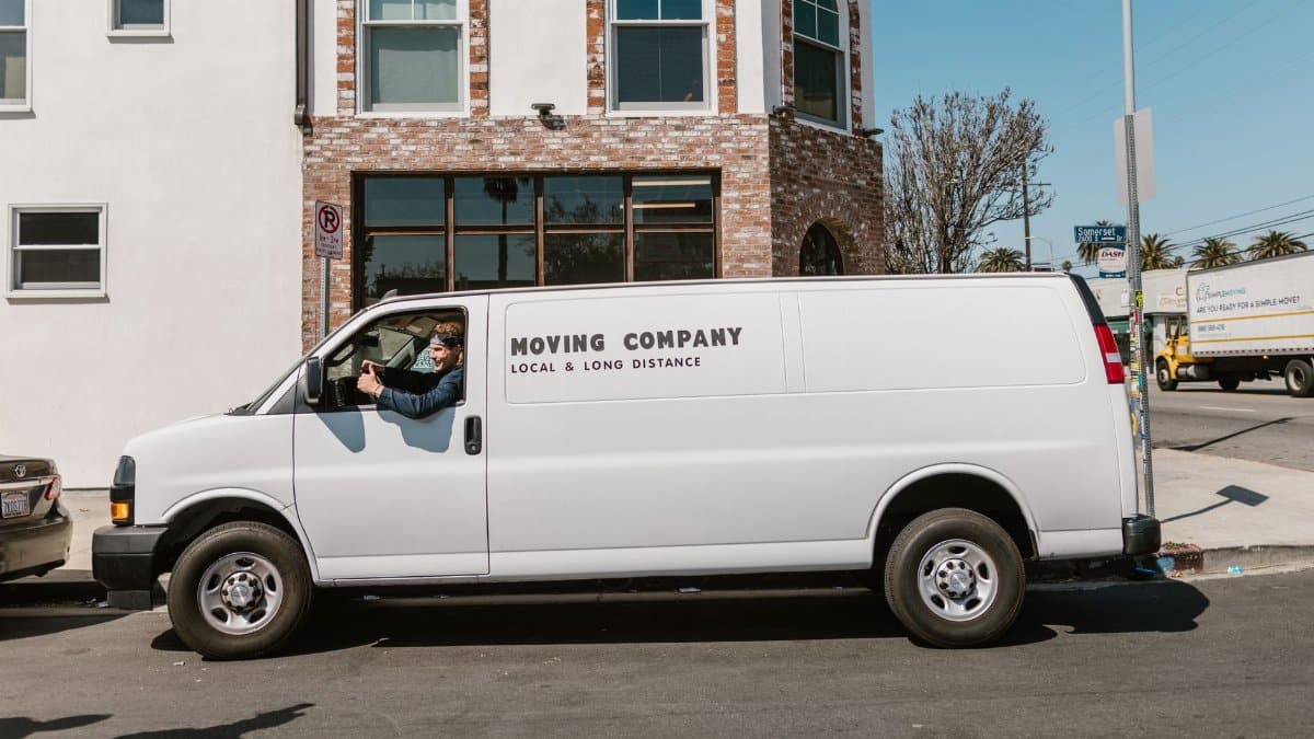 White moving company van parked on city street on a sunny day, showcasing local and long distance services.