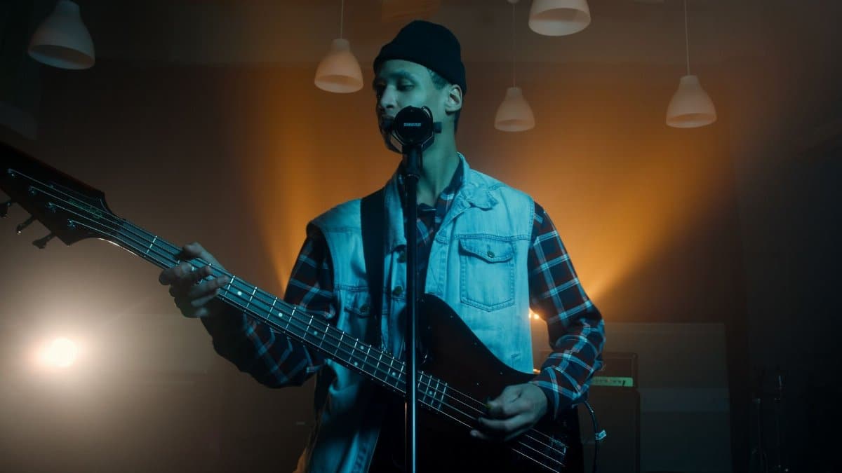 Musician performing on stage with an electric guitar under dramatic lighting.