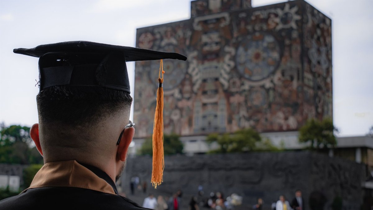 A graduate in a cap and gown at UNAM Central Library, symbolizing academic achievement in Mexico City.