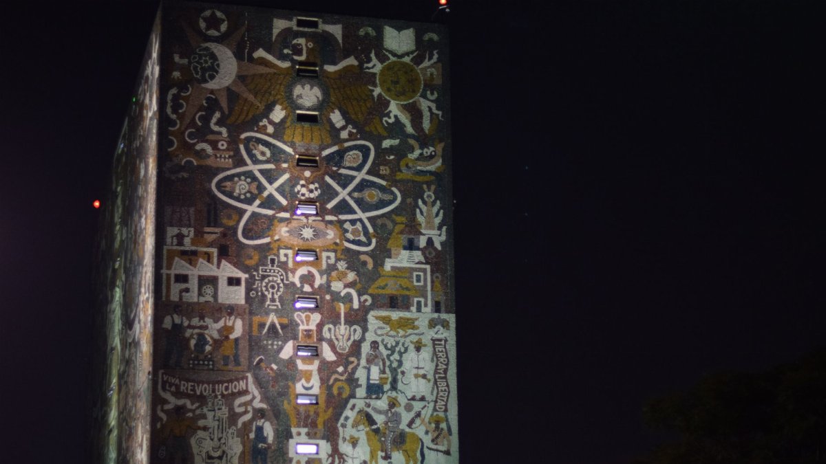 Mosaic facade of UNAM's library in Mexico City illuminated at night, a cultural landmark.