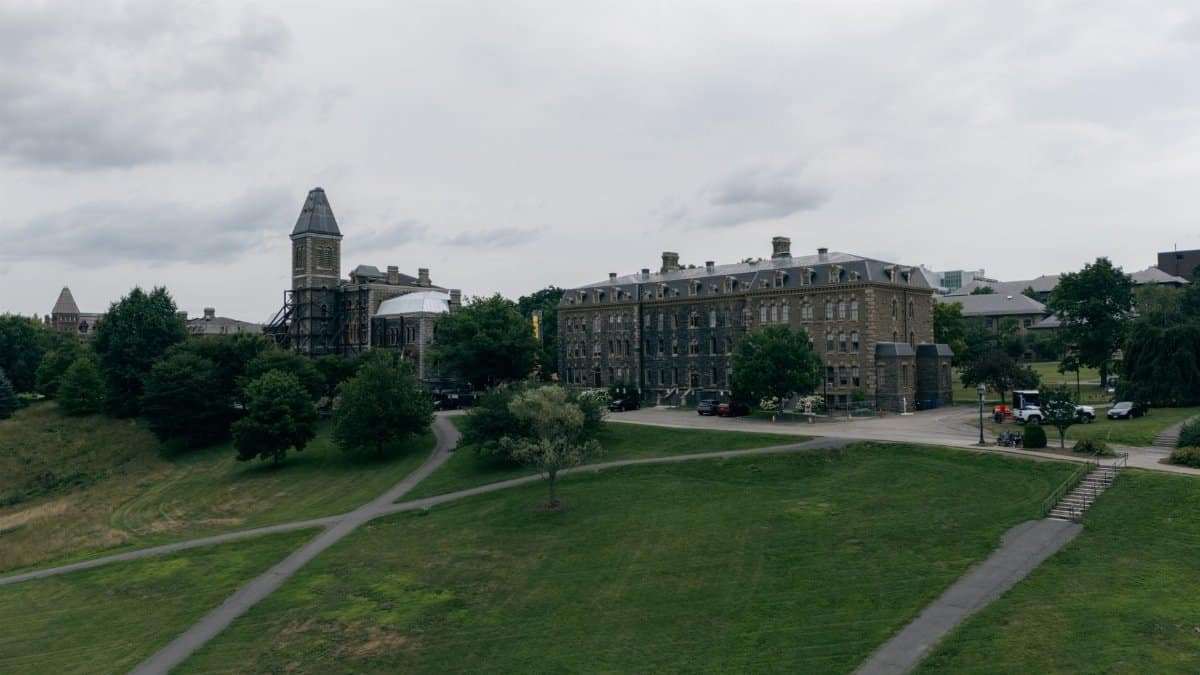 Aerial view of a historic campus building surrounded by lush greenery under an overcast sky.