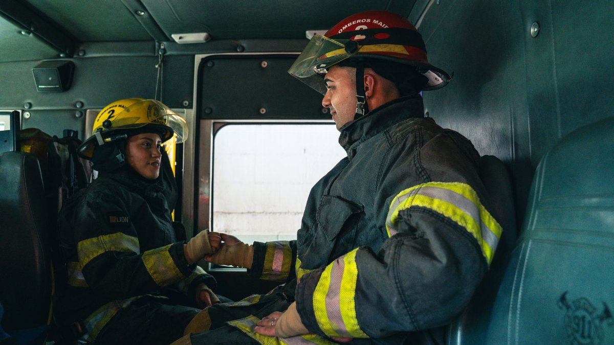 Two firefighters inside a firetruck, sharing a moment of teamwork and readiness.