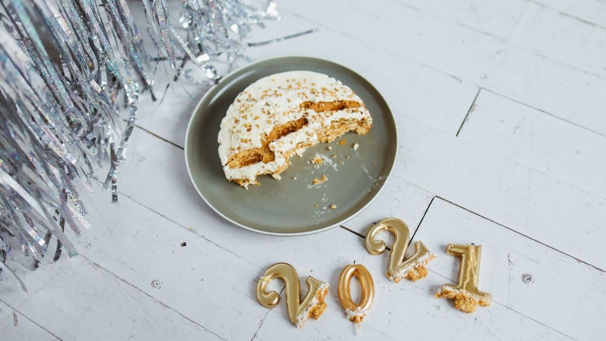 Half-eaten cake with 2021 candles on wooden floor, ideal for New Year celebration themes.