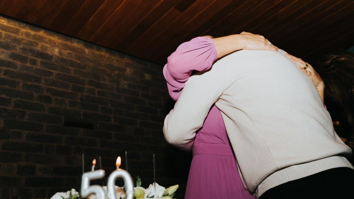 A joyful 50th birthday celebration with a heartfelt hug next to a cake.