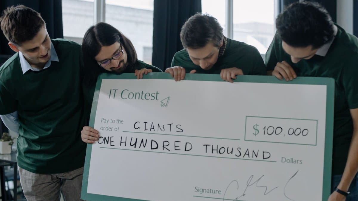 Excited startup team holding a $100,000 check after winning an IT contest, showcasing their success.