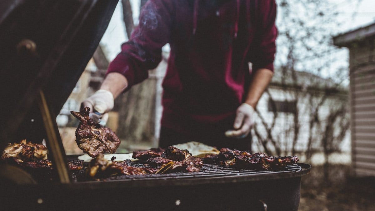 A person grilling meat outdoors in a Chicago backyard, capturing cozy barbecue vibes.