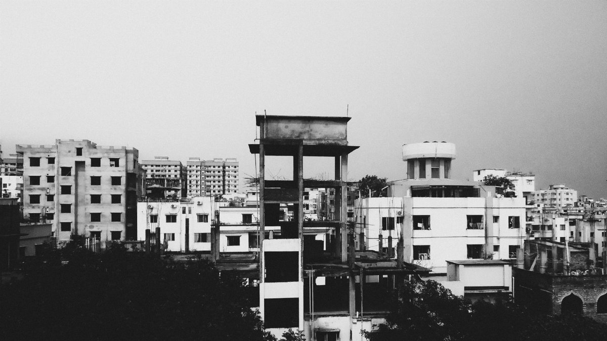 A monochrome view of urban buildings in Dhaka, showcasing residential and unfinished structures.