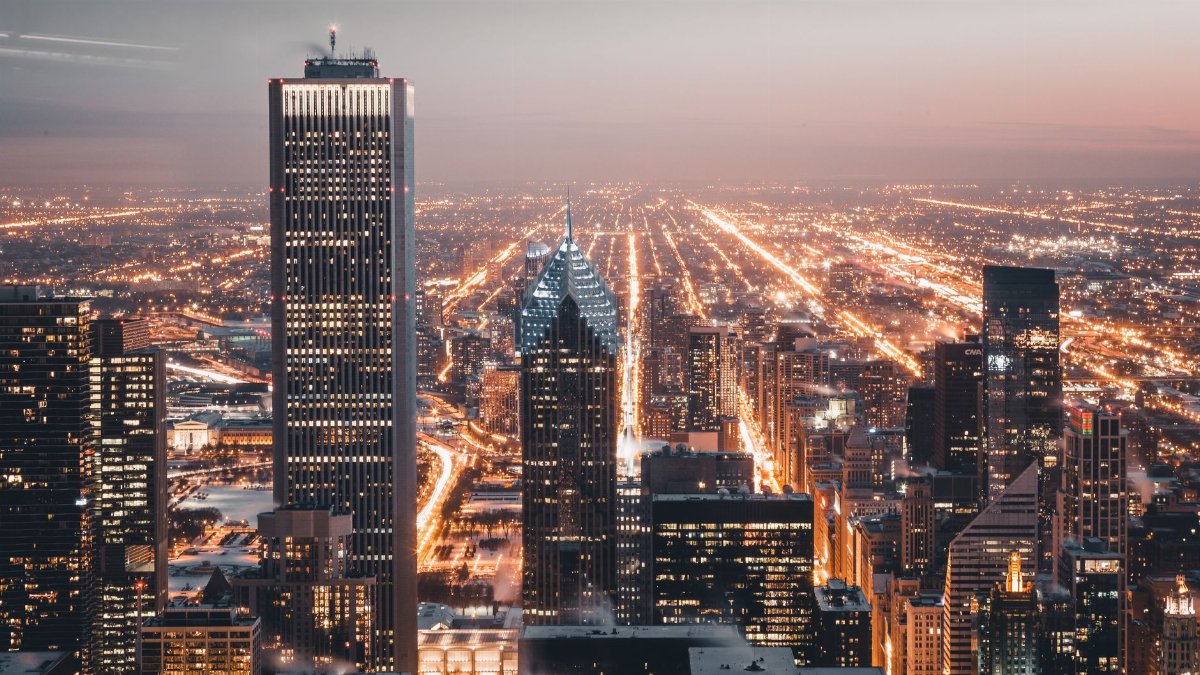 Aerial view of Chicago's illuminated skyline at dusk, showcasing vibrant city lights.