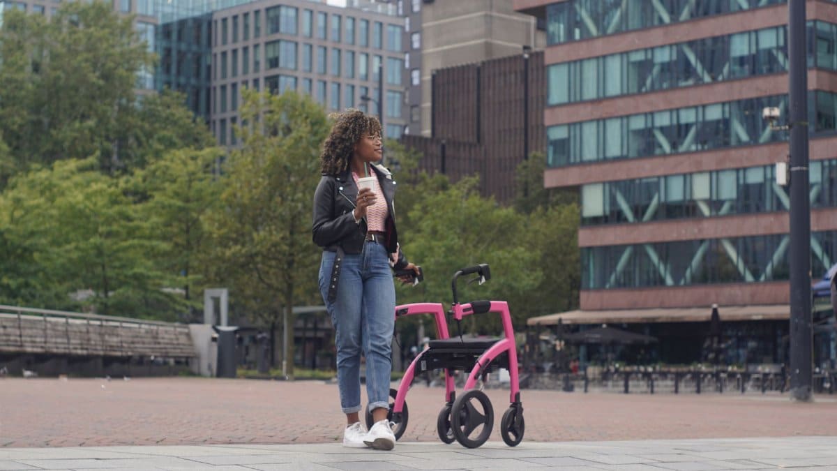 A young woman with a mobility aid, enjoying coffee in a Rotterdam city square.
