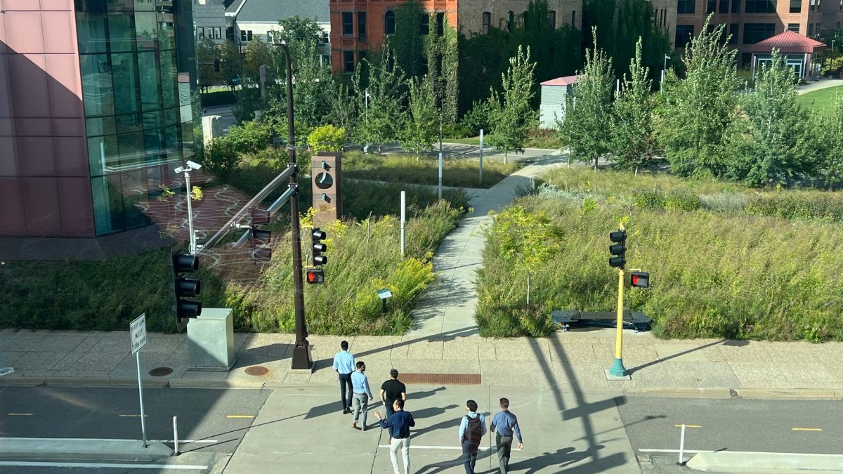 Aerial view of a city pathway with pedestrians surrounded by urban buildings and greenery.