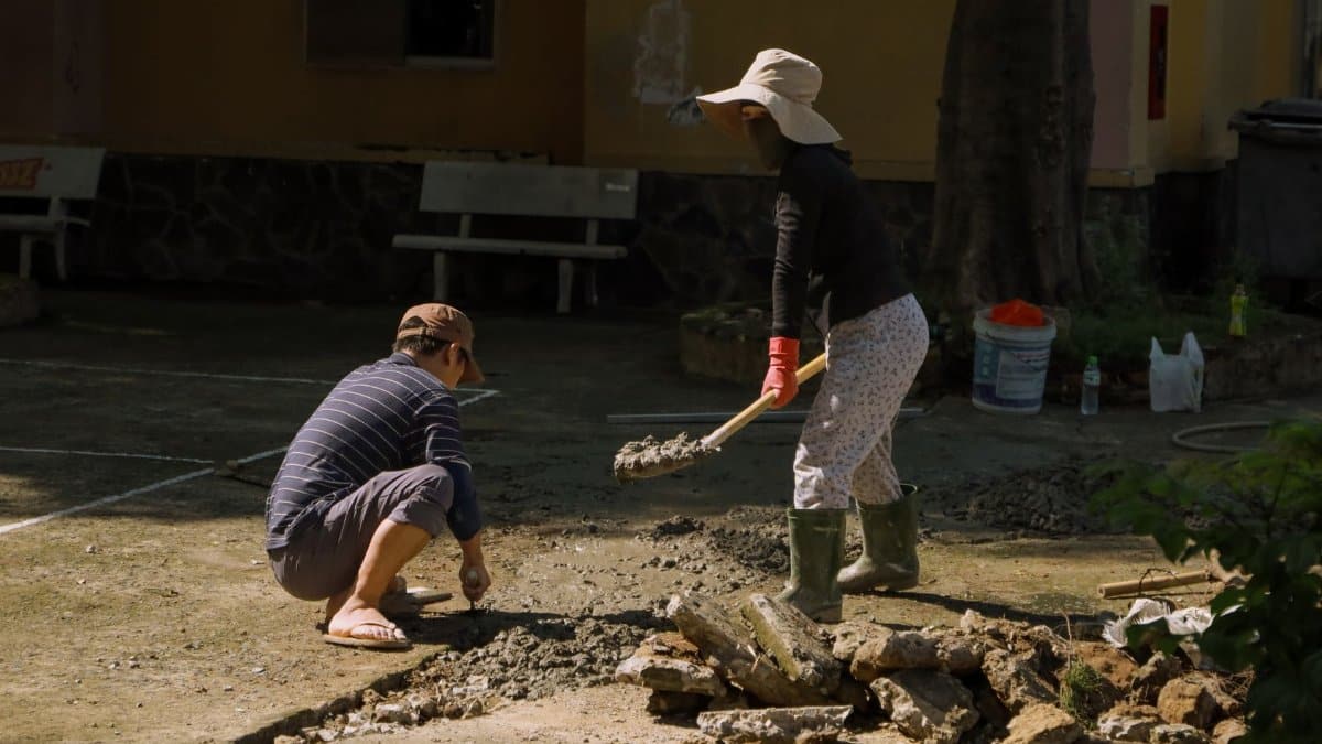 Two people engaged in concrete work outdoors in Hồ Chí Minh City, Vietnam.