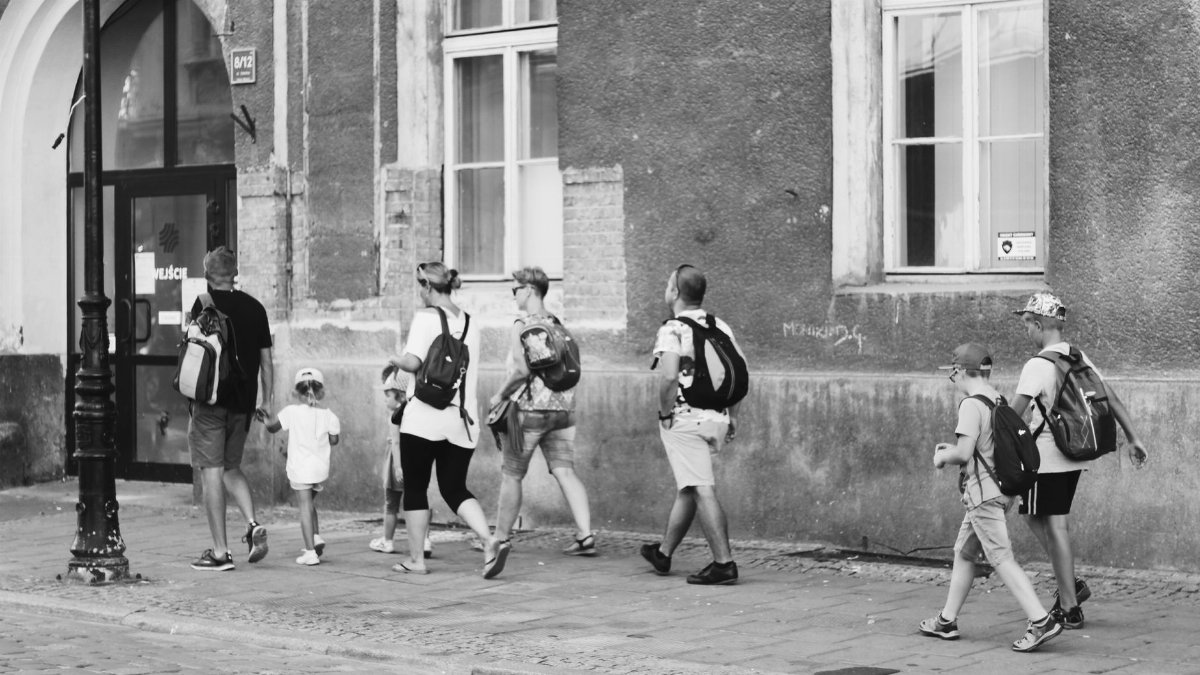 A group of people stroll together along a city street, exuding togetherness and exploration.