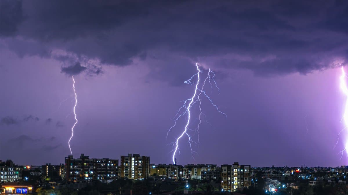 Vivid lightning strikes illuminate city skyline during a stormy night, showcasing nature's power.