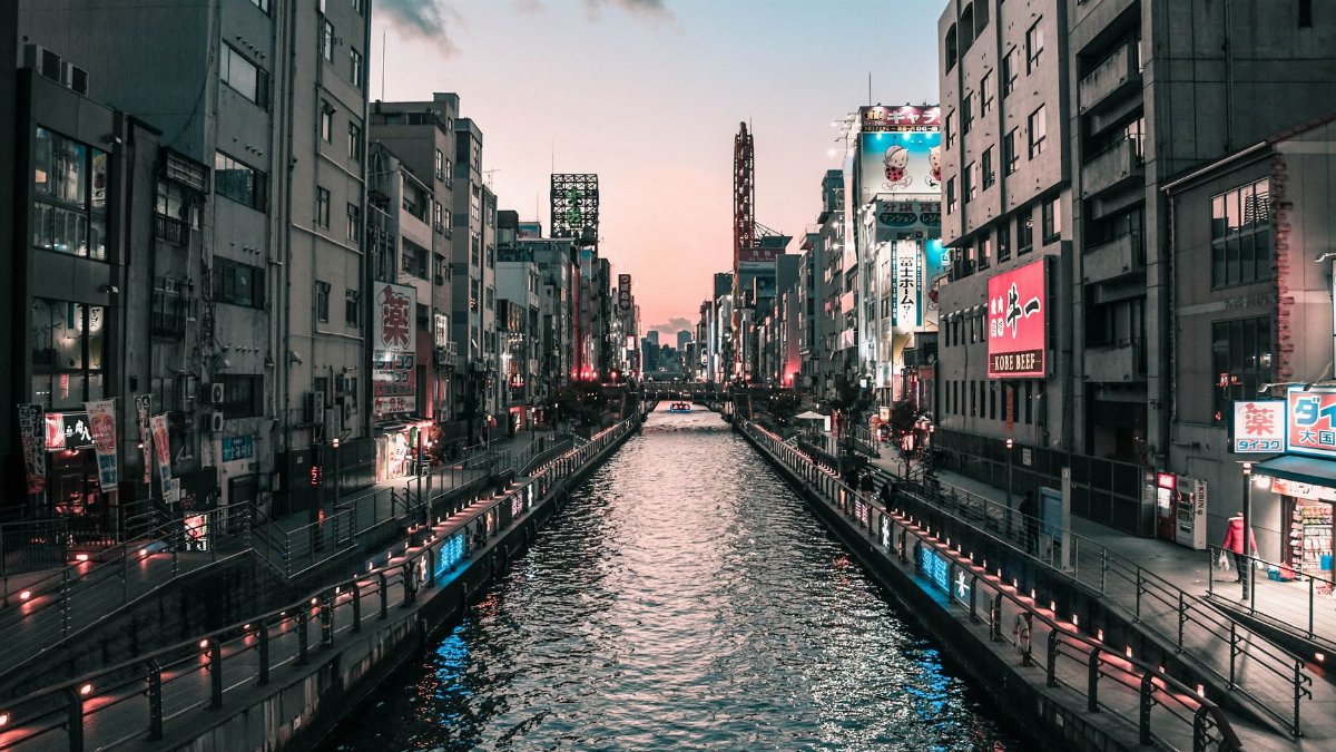 Stunning view of Dotonbori Canal in Osaka, Japan at twilight with vibrant city lights reflecting on the water.