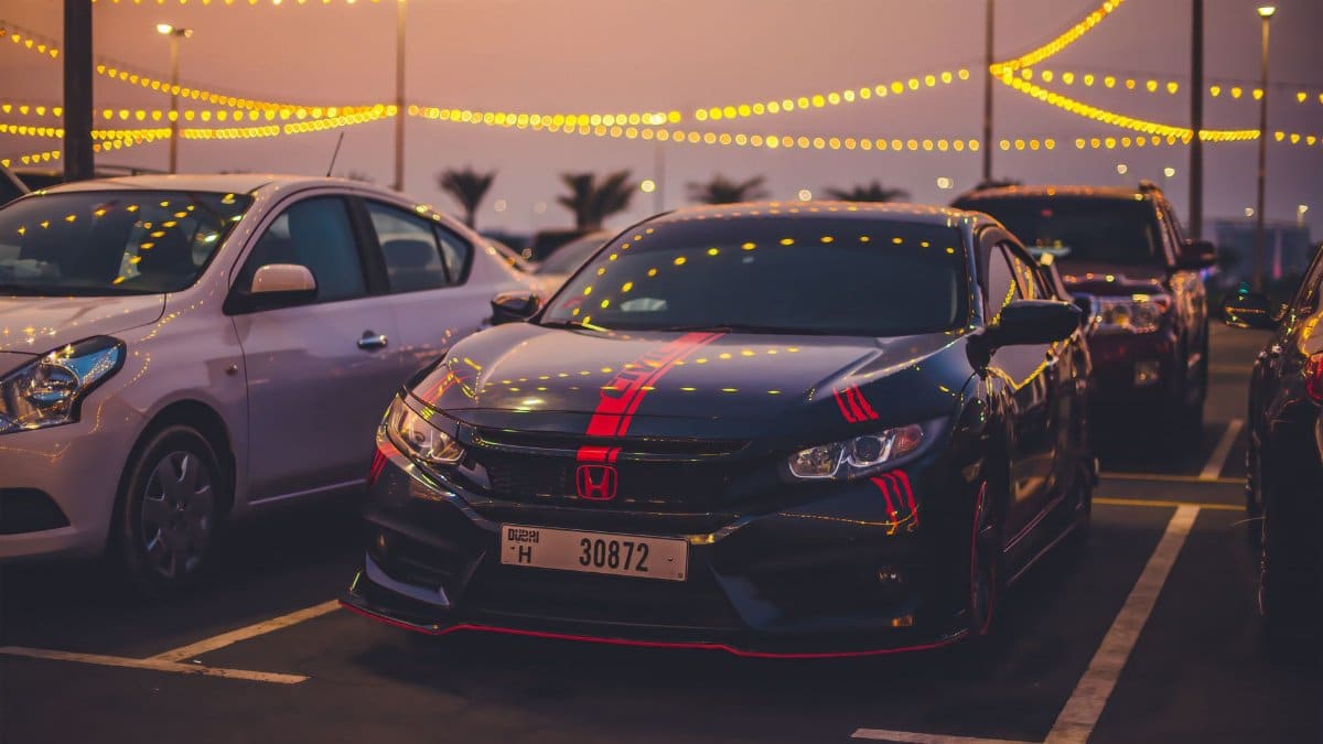 Honda Civic car parked under decorative lights in a vibrant parking lot during twilight.