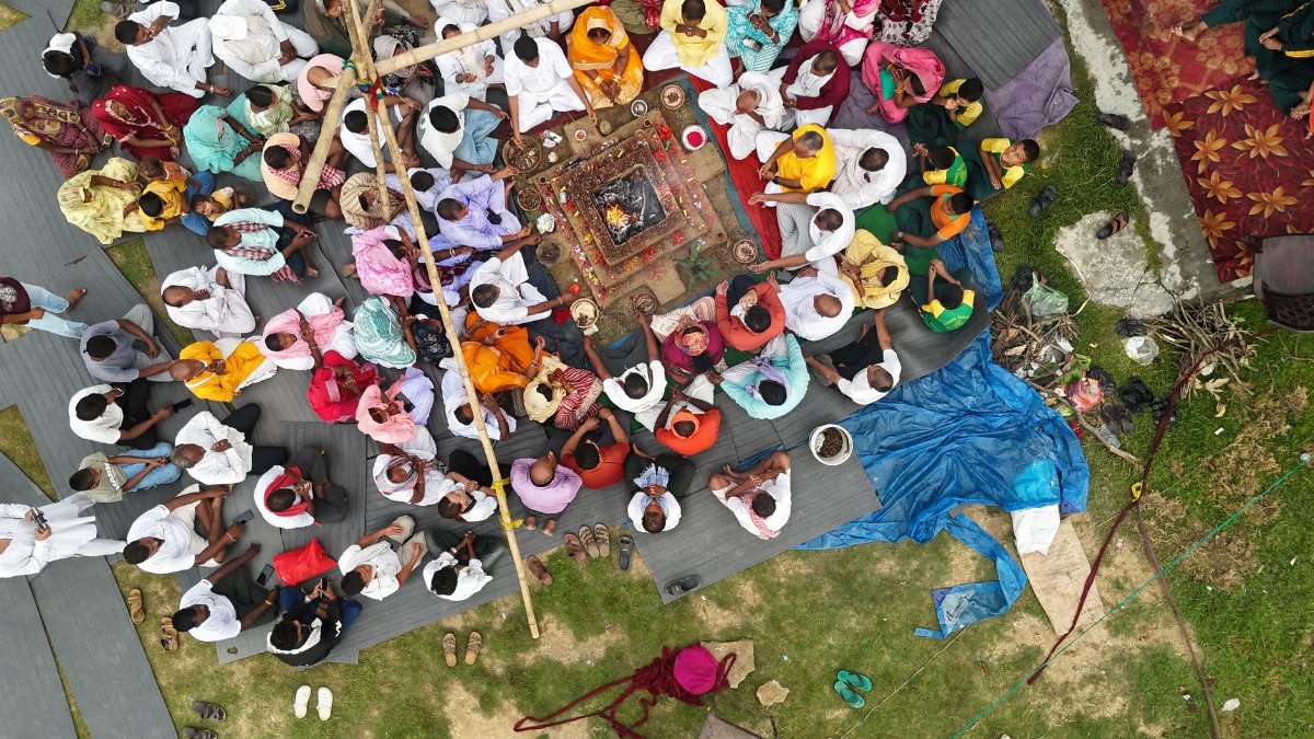 Aerial view of a traditional Indian ceremony with participants in colorful attire sitting around a central ritual fire.