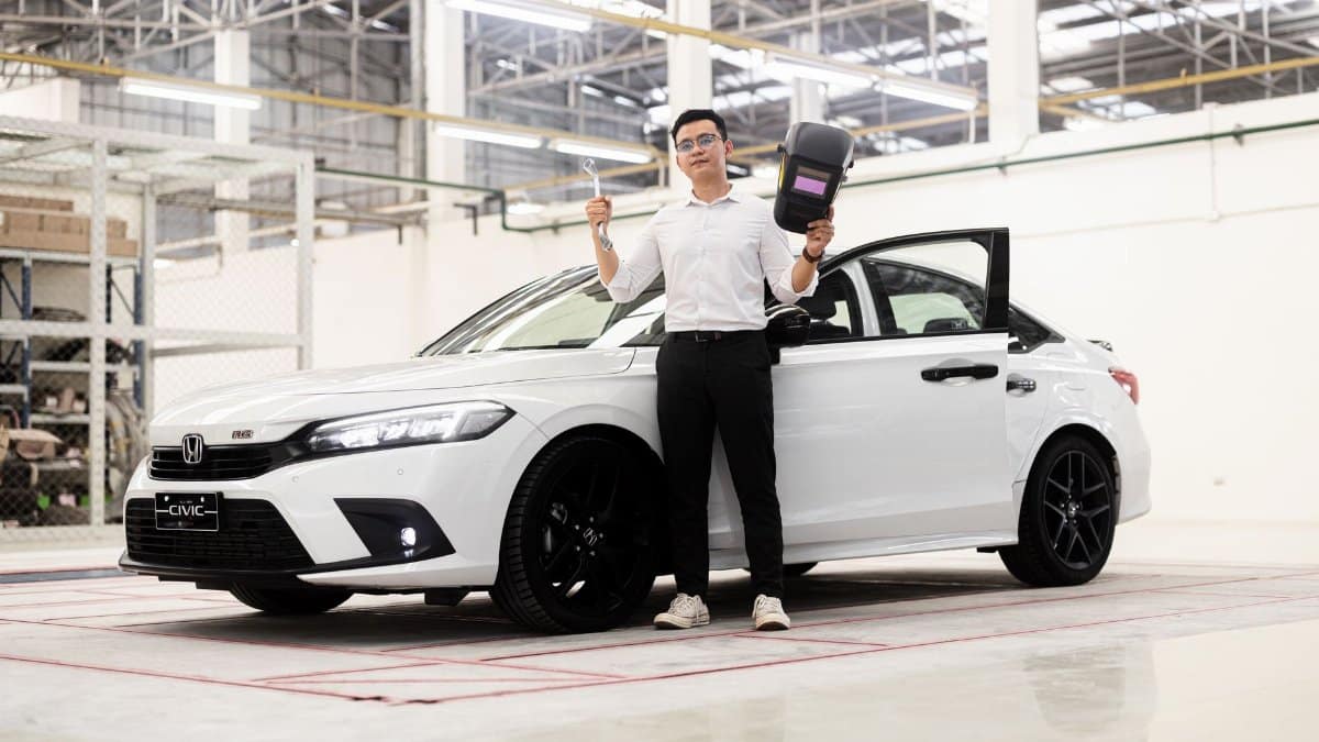 Man holding tools near a Honda Civic in a Phnom Penh automotive workshop.
