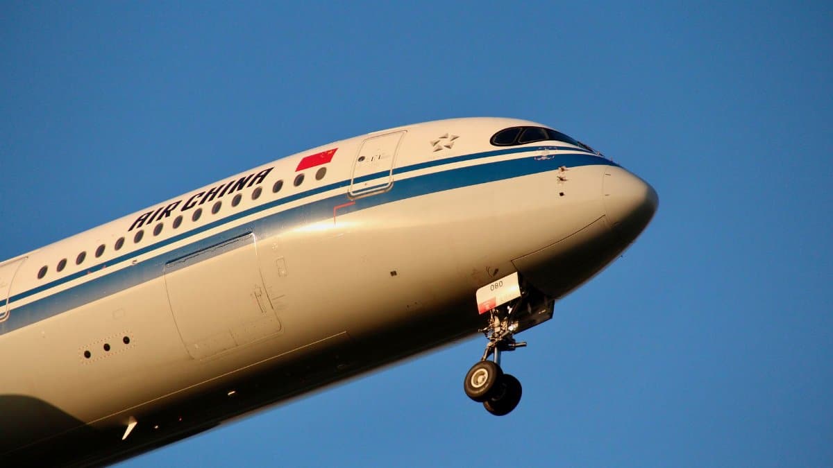 Close-up of an Air China passenger plane flying against a clear blue sky, showcasing aviation dynamics.
