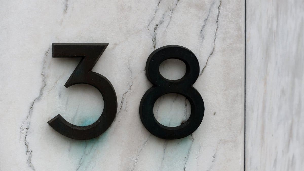 Close-up of house number 38 on a marble wall, minimal and modern design.