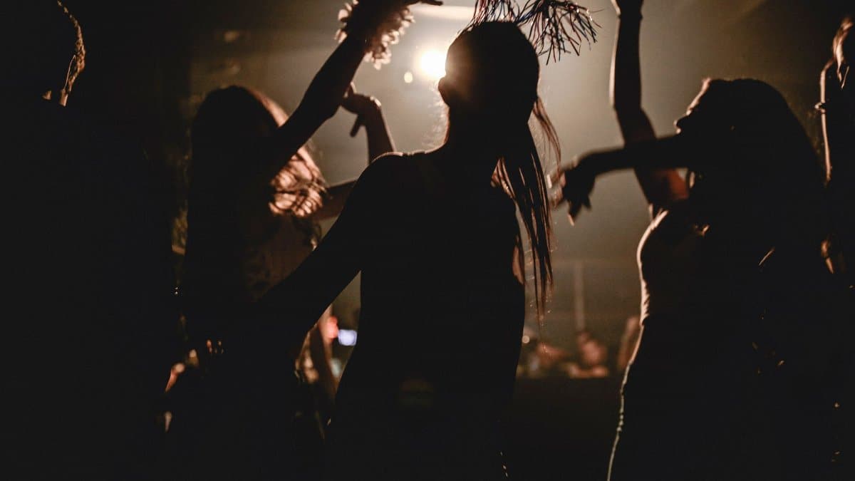 Silhouetted partygoers dancing with dynamic lighting at a lively club night.