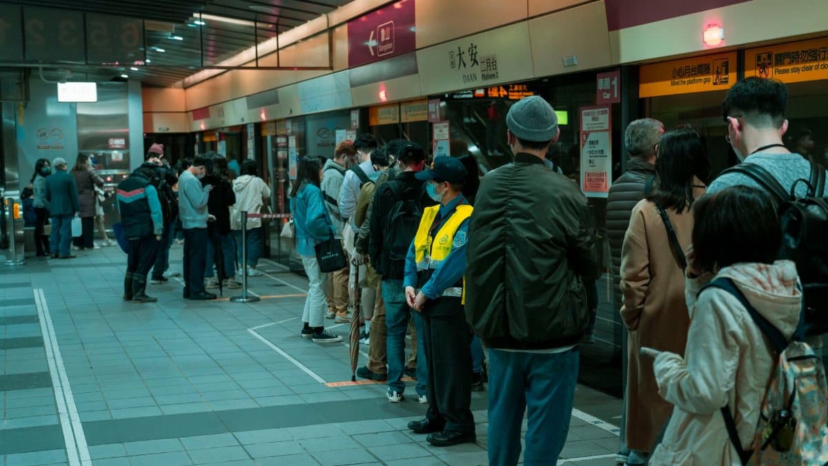 Commuters line up at a subway station platform, showcasing public transportation dynamics.