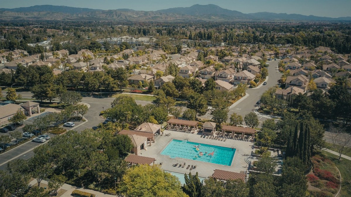 Aerial shot of a suburban neighborhood featuring a community swimming pool on a sunny day.