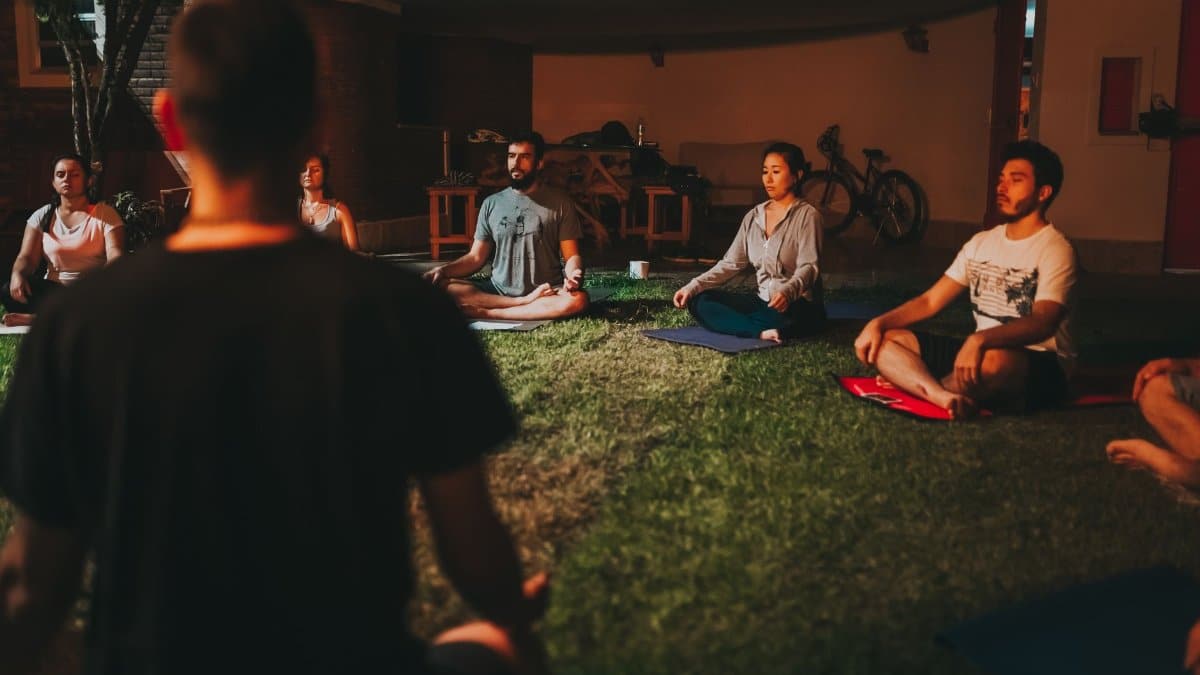 A diverse group of people meditating outdoors on a summer night.