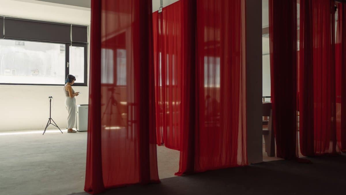 Modern studio scene with a woman, red curtains, and photography equipment.