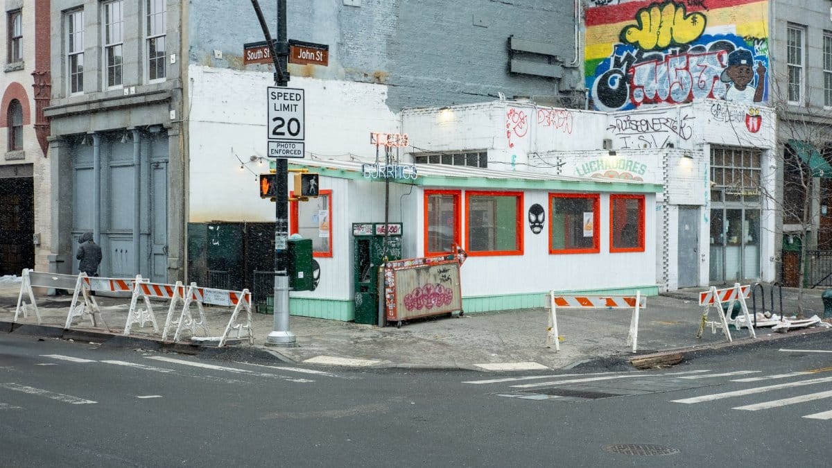 Street corner in snow with burrito stand and graffiti in New York City.