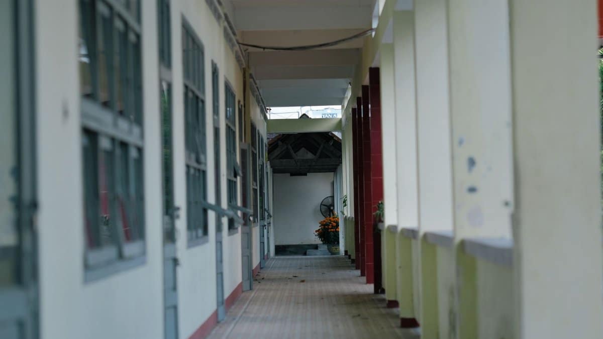 A serene, empty school corridor with soft natural lighting and open windows.