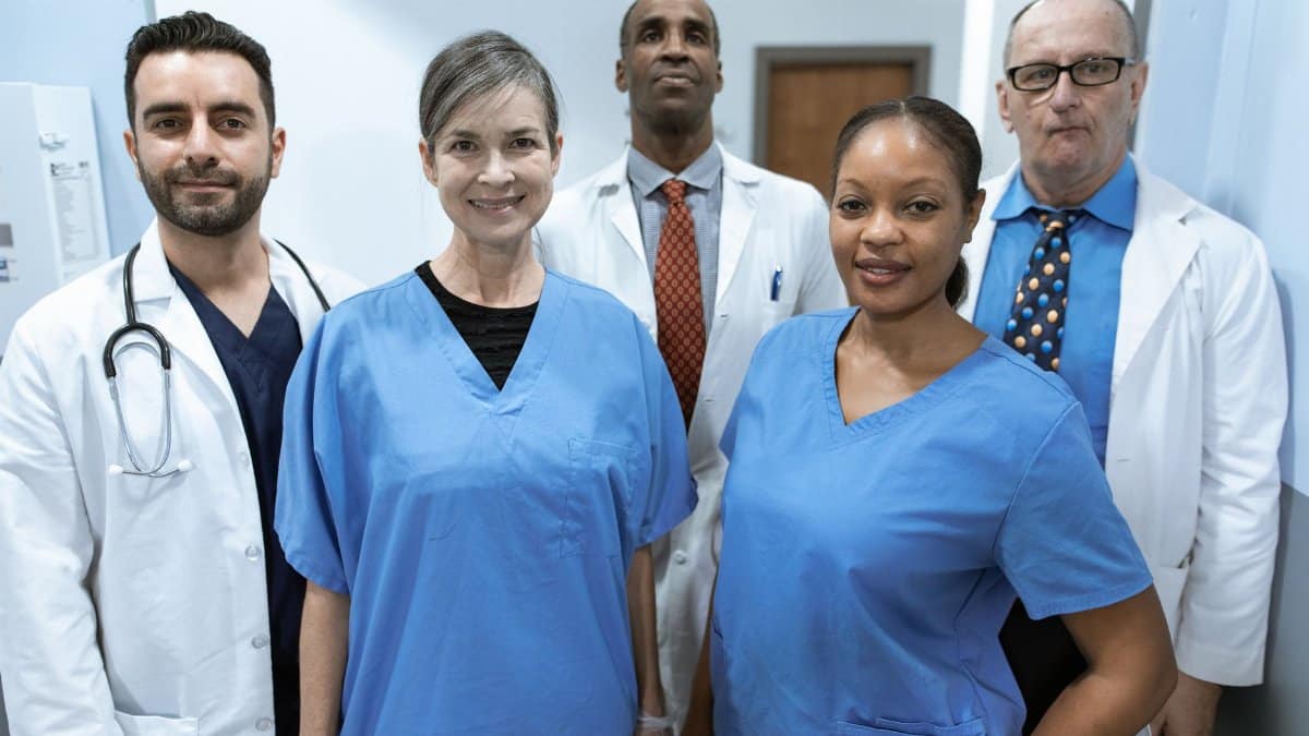 Group of diverse healthcare professionals posing confidently indoors.
