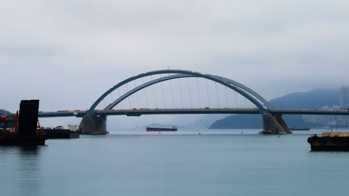Bridge spanning across calm waters with a foggy backdrop, creating a serene cityscape.