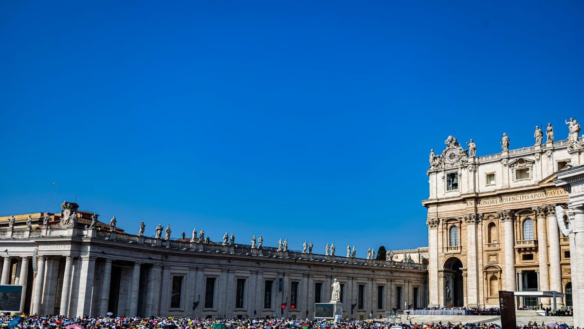 Vibrant crowd at St. Peter's Basilica in Vatican City under a clear blue sky.