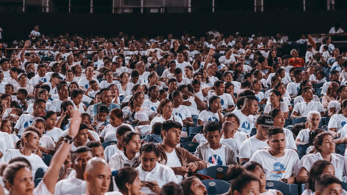 A diverse crowd in matching shirts at a stadium event indoors.