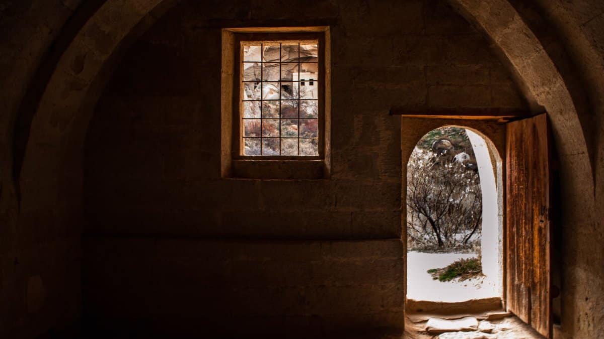 Explore the rustic charm of a medieval interior with a stone archway, window, and open wooden door.