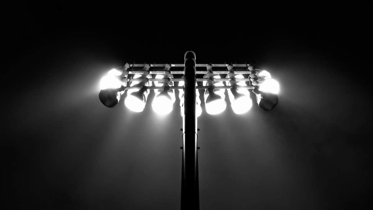 Black and white photo of stadium floodlights illuminating the night sky in Boston.