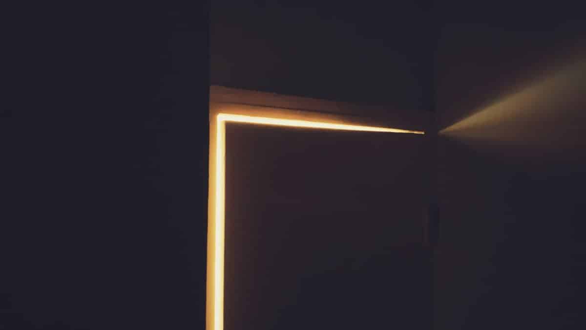 Beam of warm light coming through doorway with closed door into dark room