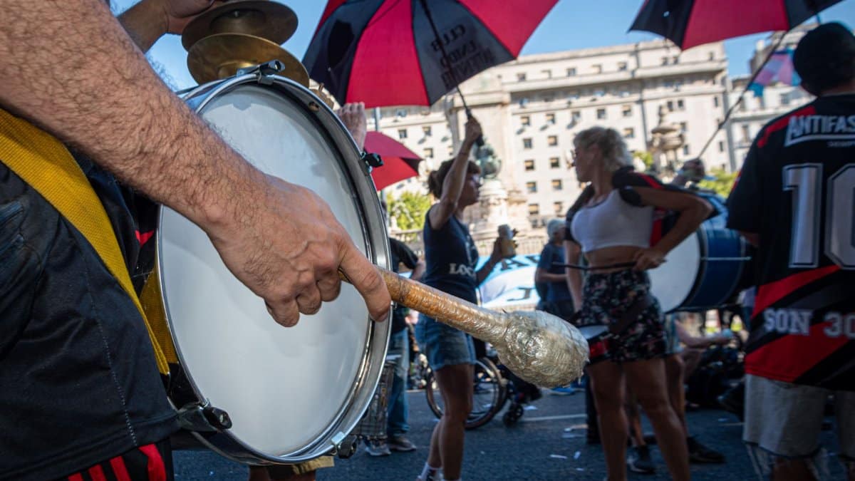 Dynamic street parade in Buenos Aires featuring colorful umbrellas and drummers.