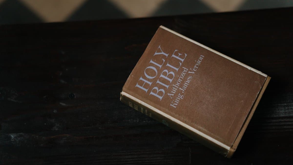Close-up of Holy Bible resting on a dark wooden table, symbolizing faith and spirituality.