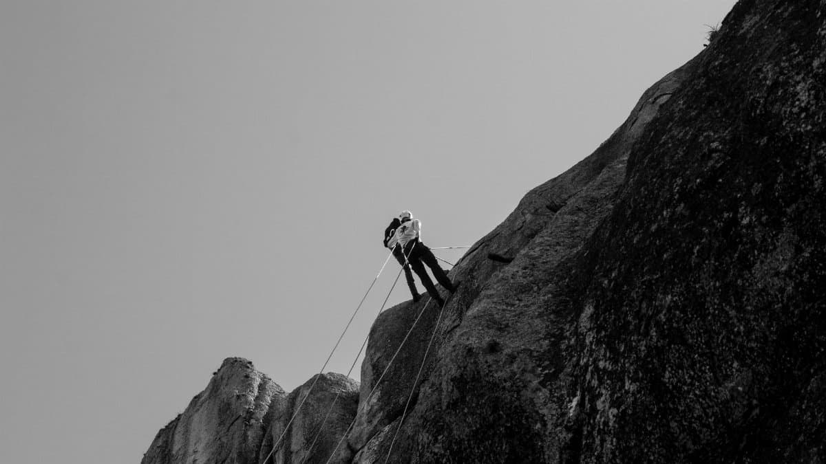 Black and white image of a climber conquering a steep cliff, showcasing strength and determination.
