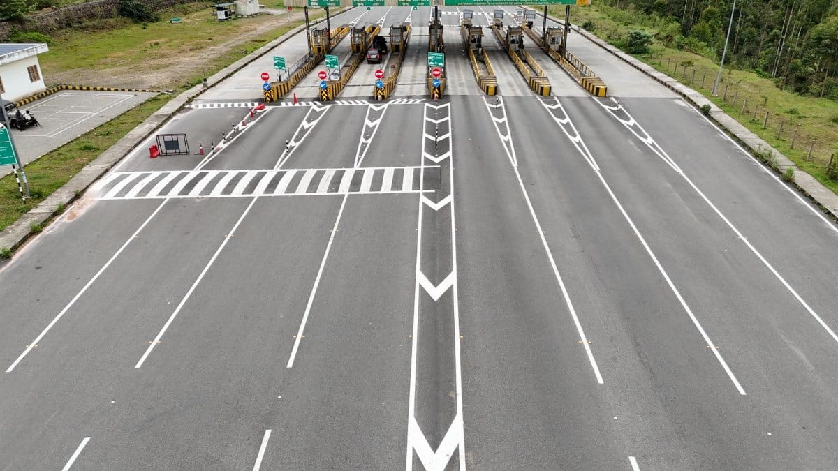 Aerial shot of an empty multi-lane toll booth on a highway surrounded by greenery.